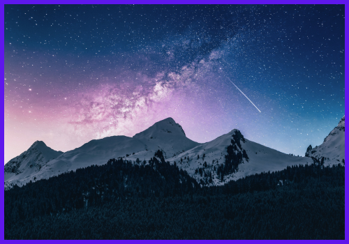 Snow-capped mountains at dusk. In the foreground, a dark forest covers the lower elevations. The sky is blue and purple with the Milky Way, numerous stars and a streaking meteor visible.