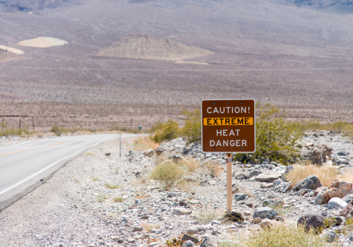 Photo of a high desert visit; in the foreground a highways sign reads, "Caution! Extreme Heat Danger."