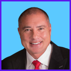 A smiling man with very short hair in a suit with a red tie