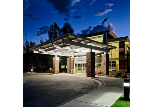 Photo of a building with a tall, covered portal, glass front doors & red sandstone facade