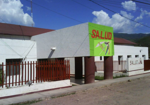 Photo of a 1-story, white & brown building with a covered entrance; "Salud" is above the door