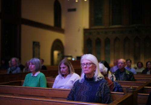 Several congregants sit silently with eyes closed meditating