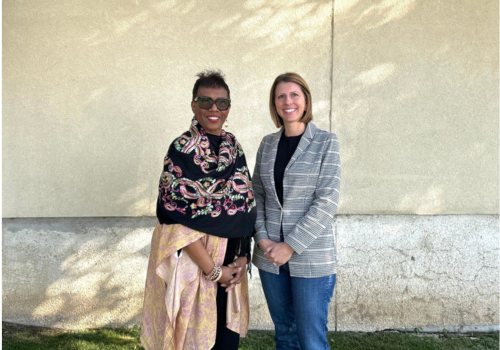 Dannette Smith and Erin Wester stand next to each other in front of a concrete wall