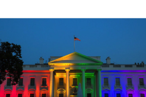 Photo of the White House with rainbow lights reflecting off the facade.