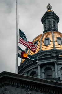 A glimpse of the gold dome and the U.S. and State of Colorado flags at half-staff