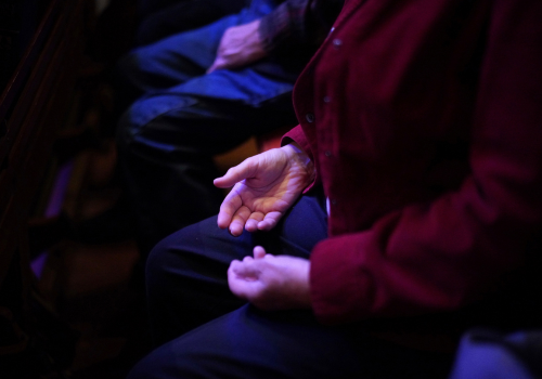 Photo of a white person's hands resting in her lap.