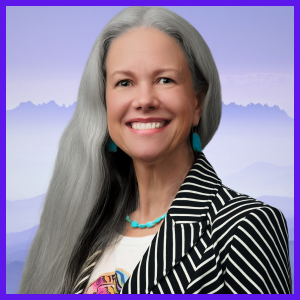 A mixed Indigenous woman with long, silver hair and wearing a black and white striped suit jacket