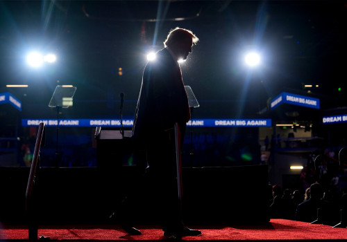 Trump's form is highlighted by background lighting, but he is in shadow