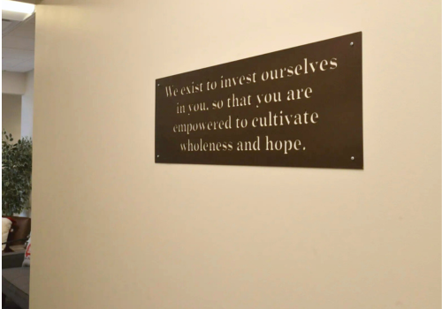 Wall plaque saying, "We exist to invest in ourselves in, so you are empowered...for wholeness & hope